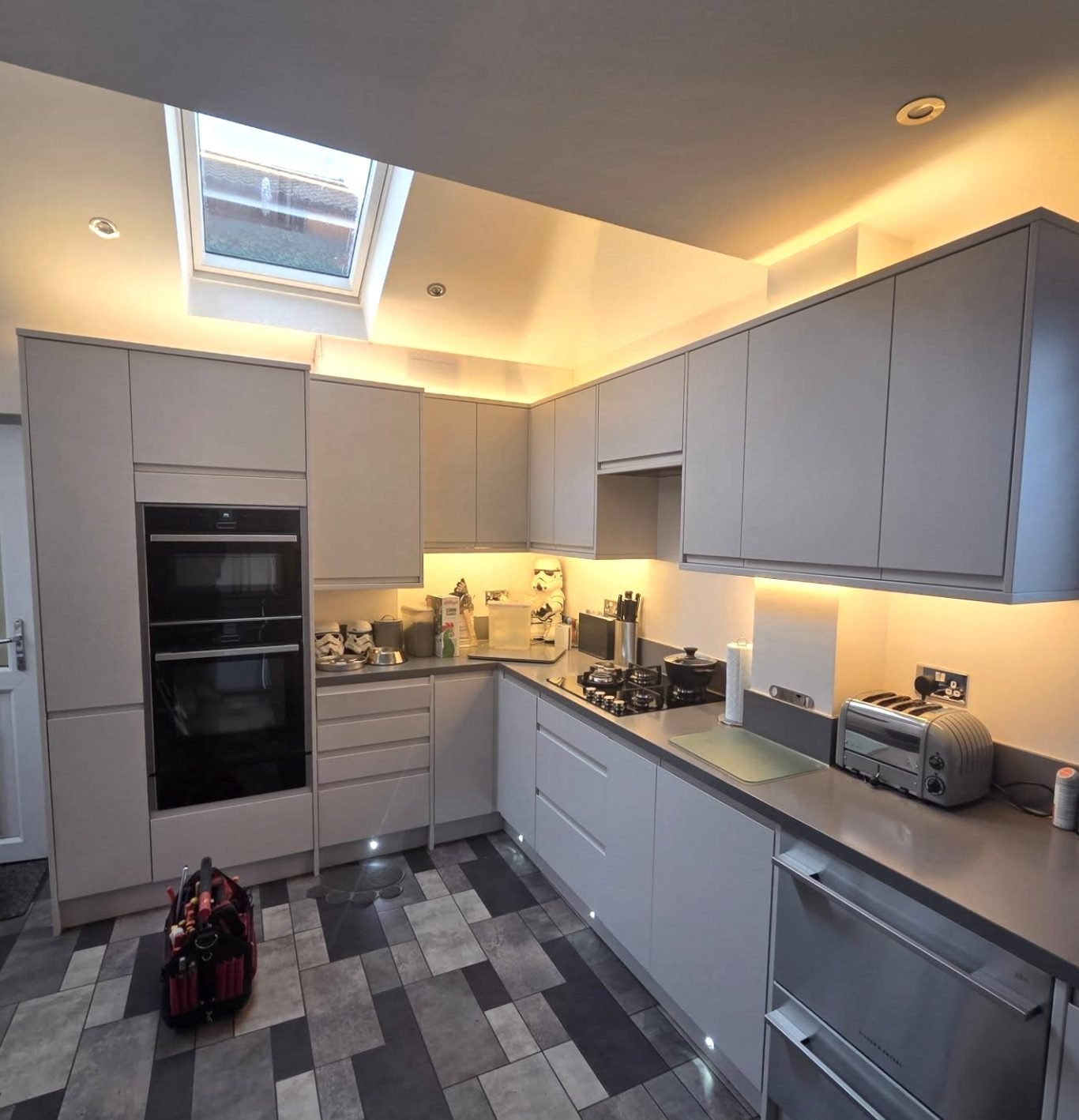 Grey kitchen with warm LED pelmet lighting and recessed downlights